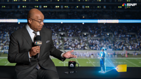 Best Buy "spokeshologram" Gram helps NBC Sports' Mike Tirico get ready for kickoff.