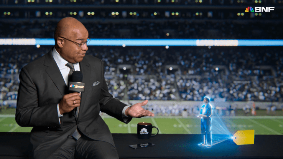 Best Buy "spokeshologram" Gram helps NBC Sports' Mike Tirico get ready for kickoff.